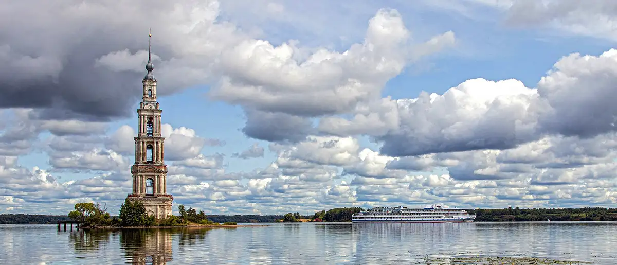 ein Flusskreuzfahrtschiff vor dem Glockenturm der gefluteten Nikolaus-Kathedrale in Kaljasin